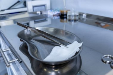 Görüntü cerrahi makas ve gazlı bez içeren bir cerrahi tepsi sergiliyor. Klinik sağlık ortamında paslanmaz çelik bir yüzeye karşı dizilmiş..