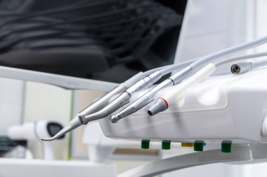 Bir çalışma istasyonunda dinlenen diş aletleri ve araçlarına yakından bakıldığında, dişçilerin oral sağlık hizmetleri ve ileri tedavi seçenekleri sunmak için kullandığı temel ekipmanlar sergileniyor.