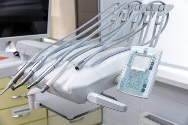 Profesyonel bir diş sağlığı kliniğinde düzenli bir düzenleme olduğunu belirten, hijyen ve erişim kolaylığını vurgulayan, titiz aletler ve kontroller gösteren gelişmiş bir diş ünitesi ele geçirilmesi.