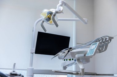 Modern bir klinikte hasta rahatlığını arttırmak ve diş tedavisini etkili bir şekilde kolaylaştırmak için tasarlanmış yüksek teknoloji aletleri ve monitörle donatılmış gelişmiş bir diş sağlığı koltuğu..