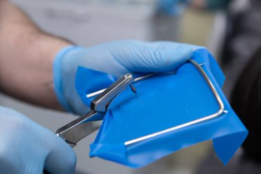 Eldivenler üzerinde titizlikle çalışan bir tıp uzmanı mavi sterilize bir örtü hazırlarken klinik ortamdaki temizlik ve güvenliği sağlarken cerrahi ekipmanlarla da ilgilenir..