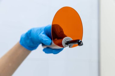 Bir sağlık uzmanı, klinik bir ortamda hasta bakımı ve teşhisinde yenilik ve hassasiyeti vurgulayan, turuncu optik aksesuar içeren gelişmiş bir tıbbi cihaz bulundurur..