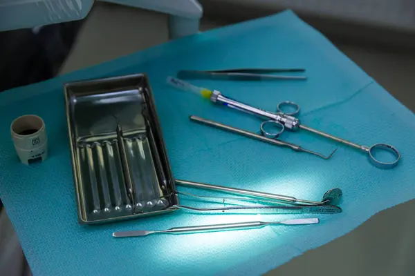 Bu resim çeşitli cerrahi gereçleri titizlikle mavi bir cerrahi minder üzerinde düzenleyerek çeşitli tıbbi işlemler ve uygulamalar için gerekli hassas araçları vurgular..
