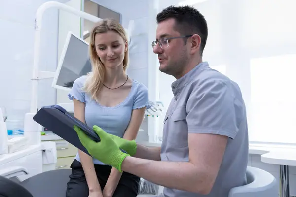 Bir diş hekimi, hastaya oral sağlıkları hakkında bilgi verir ve modern teknolojiye sahip, parlak, iyi donanımlı bir dişçi kliniğinde rahatlatıcı bir deneyim yaratır..