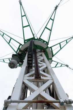 Bu resim, gökyüzü bulutlu bir zemine karşı karmaşık mühendislik sergilenen, belirgin yeşil ve beyaz tasarımı ile karakterize bir endüstriyel kule yukarı bir görünüm içerir..