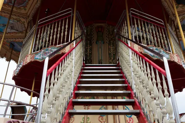 Görüntü, güzel hazırlanmış bir atlıkarıncaya çıkan süslü bir merdiven sergiliyor. Karmaşık tasarımı ve canlı renklerini vurguluyor. Nostalji ve neşe çağrıştırıyor..