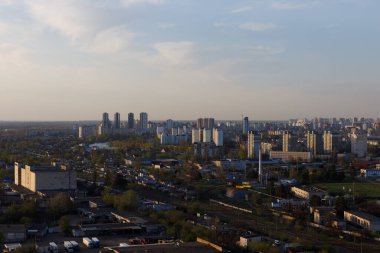 Bu resim bir şehrin çarpıcı bir görüntüsünü sergiliyor, yeşillik ve ticari binaların karışımını sergiliyor, kentsel gelişim ve doğanın birlikte var oluşunu gösteriyor..