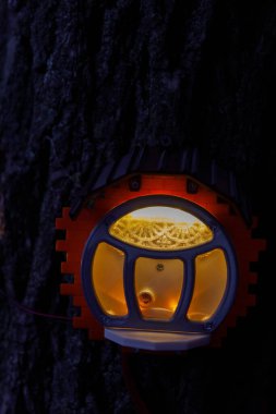 Bir ağaca monte edilmiş yaratıcı bir birim, yumuşak, sıcak bir ışık yayıyor, içindeki dokulu desenleri ortaya çıkarıyor, gecenin karanlığında gizemli ama davetkar bir ortam yaratıyor..