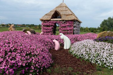 Bu büyüleyici bahçe, sevimli hayvan figürleri ve büyüleyici sazdan bir ev gibi kaprisli dekorasyonlarla çerçevelenmiş pembe ve mor tonlarda canlı bir çiçek dizisine sahip..