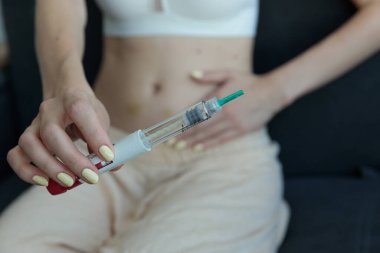 Görüntü, bir insanın elinin şırıngayı kavraması, midesinin üzerinde durması, kişisel sağlık yönetimi ve kendi kendini idare etmenin önemini simgeliyor..