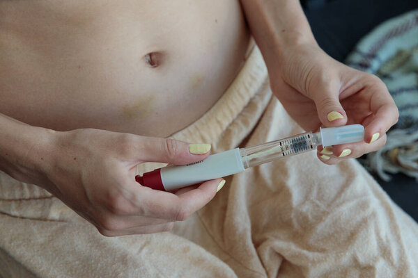 This image showcases a close-up of a person holding a medical injection device, focusing on the details of its mechanism in a relaxed indoor setting, emphasizing health awareness.