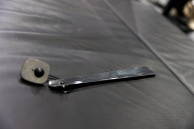 Parlak bir metal aracı, bir perakende güvenlik etiketleme kurulumu veya ürün görüntüleme düzenleme yansıtan, dokulu siyah bir yüzey üzerinde mat siyah kare etiketi yanında dinlenir.