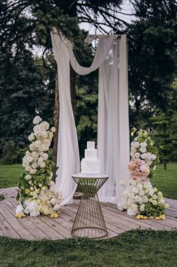 Resmedilmeye değer bir düğün yeri eşsiz bir kaidede şık bir pasta sergiliyor. Etrafı güzel çiçek aranjmanları ve yumuşak örtülerle çevrili. Doğada rüya gibi bir kutlama için mükemmel..