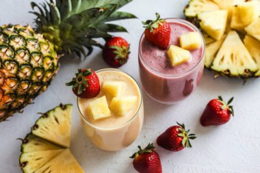 Taze ananas ve çilekli smoothie ile dolu iki bardak.