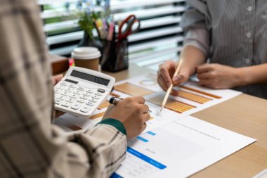 Bir kadın elinde hesap makinesi ve kalem tutuyor. Hesap makinesine bakıyor ve bir şeyler hesaplıyor gibi görünüyor.