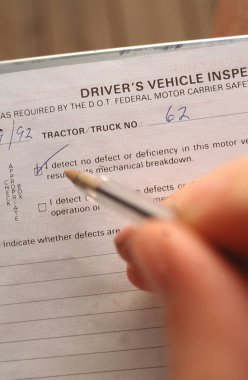 Sürücü eli kalemle, kayıt defteri sayfasının güvenlik denetimiyle ilgili kutucuğunu işaretliyor.