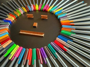 Neşe ve yaratıcılık okula geri döndü. Renkli kalemlerden, gözlerden ve ağızlardan yapılmış güzel bir güneş okul zımbalarından yapılmış gülümseyerek ve fotoğrafı aydınlatarak..