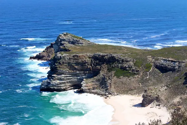 Mavi suyu ve beyaz sörfü olan çalkantılı okyanus.
