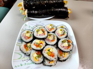 Taze sebzelerle, baharatlı pirinçlerle ve gevrek yosunlara sarılmış lezzetli proteinlerle dolu nefis kimbap dürümleri. Her ısırıkta lezzet ve dokuların mükemmel bir kombinasyonu.