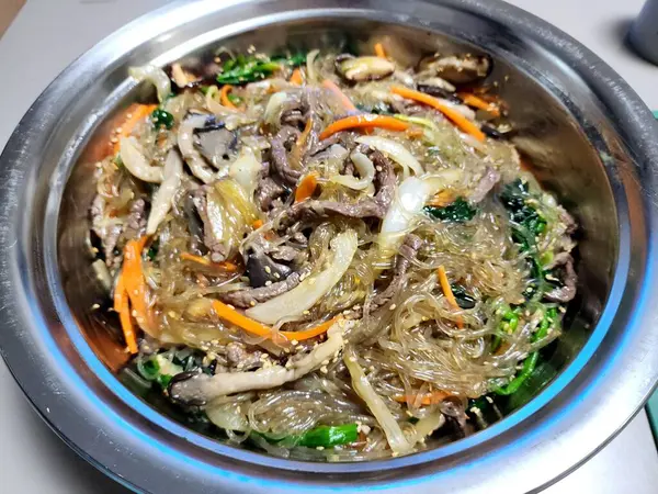 Canlı bir tabak japchae, kızarmış cam şehriye, renkli sebzeler, ve lezzetli soya sosuyla kaplanmış taze et. Klasik bir Kore favorisi.!