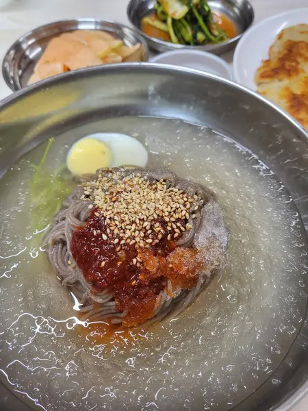 Soğuk ve ferahlatıcı Kore naengmyeon eriştesi, dilimlenmiş salatalık, turp ve haşlanmış yumurta ile servis edilir. Sıcak yaz günleri için nefis, keskin bir yemek..