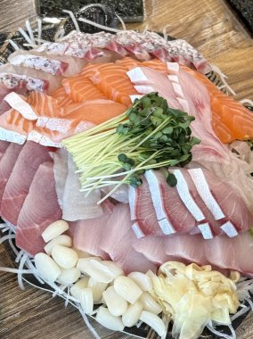 Taze ve narin sashimi dilimleri, canlı renkler ve mükemmel kesimlerle güzelce sunuluyor. Bu geleneksel Japon lezzeti kaliteli deniz ürünlerinin saf tatlarını vurgular..