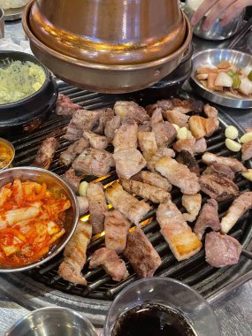Izgara samgyeopsal, kalın domuz eti dilimleri çıtır çıtır ve taze et. Klasik bir Kore barbekü deneyimi için marul, sarımsak ve sosla servis ediliyor..