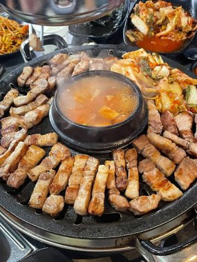 Izgara samgyeopsal, kalın domuz eti dilimleri çıtır çıtır ve taze et. Klasik bir Kore barbekü deneyimi için marul, sarımsak ve sosla servis ediliyor..
