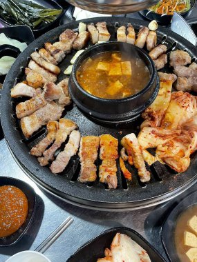 Izgara samgyeopsal, kalın domuz eti dilimleri çıtır çıtır ve taze et. Klasik bir Kore barbekü deneyimi için marul, sarımsak ve sosla servis ediliyor..