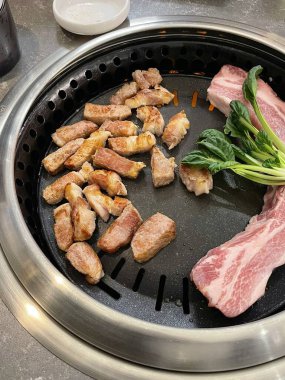 Izgara samgyeopsal, kalın domuz eti dilimleri çıtır çıtır ve taze et. Klasik bir Kore barbekü deneyimi için marul, sarımsak ve sosla servis ediliyor..