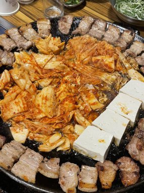 Izgara samgyeopsal, kalın domuz eti dilimleri çıtır çıtır ve taze et. Klasik bir Kore barbekü deneyimi için marul, sarımsak ve sosla servis ediliyor..