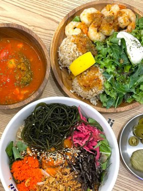 Taze, marine edilmiş balık, pirinç ve avokado, yosun ve susam tohumları gibi renkli malzemelerle dolu canlı bir poke kasesi. Sağlıklı, doyurucu ve dokuları bol bir yemek..