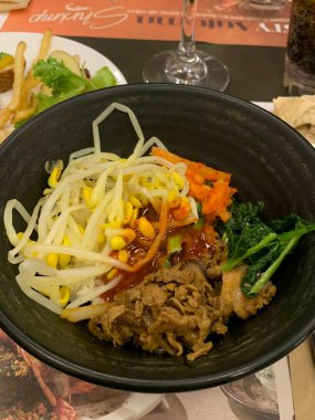 Bibimbap, çeşitli sebzeler, gochujang ve sıklıkla dilimlenmiş etin eşlik ettiği kızarmış yumurta ile süslenmiş canlı bir Kore pirinç yemeği. Karıştırıldığında, aromalı ve dengeli olur..