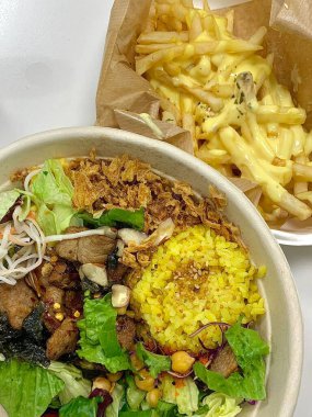 Taze balık, sebze ve pirinçli renkli bir kase yanında çıtır patates kızartması. Beklenmedik ama lezzetli, sağlıklı ısırıklar ve hoşgörülü çıtır çıtırlar..