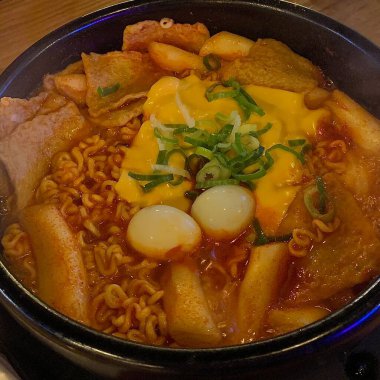 Baharatlı bir çorbada sosis, tofu, kimchi ve erişte ile dolu doyurucu bir kase Budaejjigae (Kore Ordu Güveci). Bu lezzetli yemek sıcaklık ve rahatlık getirir. Paylaşmak için mükemmel..