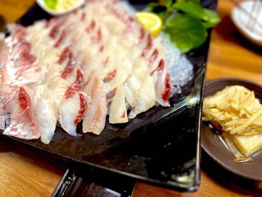 Taze ve narin sashimi dilimleri, canlı renkler ve mükemmel kesimlerle güzelce sunuluyor. Bu geleneksel Japon lezzeti kaliteli deniz ürünlerinin saf tatlarını vurgular..