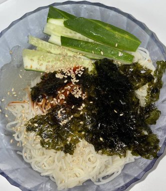 Bibimyeon, baharatlı, keskin soslu, taze sebzeli ve haşlanmış yumurtalı soğuk erişte içeren lezzetli bir Kore yemeği. Yaz yemekleri için mükemmel, canlı aromalar ve renkler sergiliyor.
