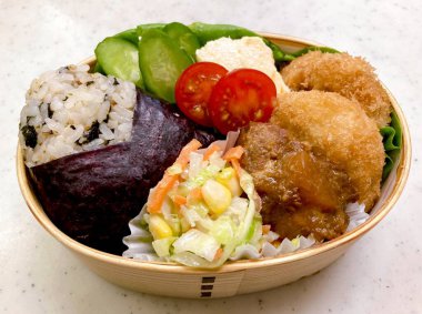 Geleneksel bir Kore dozirak 'ı. Pirinç, çeşitli banchan ve tuzlu proteinlerle güzelce düzenlenmiş. Dengeli ve görsel olarak davetkâr, canlı lezzetlerle dolu taşınabilir bir yemek..