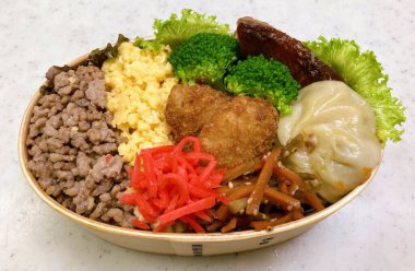 Geleneksel bir Kore dozirak 'ı. Pirinç, çeşitli banchan ve tuzlu proteinlerle güzelce düzenlenmiş. Dengeli ve görsel olarak davetkâr, canlı lezzetlerle dolu taşınabilir bir yemek..