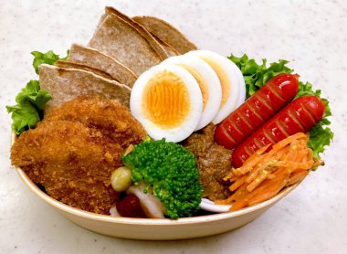 Geleneksel bir Kore dozirak 'ı. Pirinç, çeşitli banchan ve tuzlu proteinlerle güzelce düzenlenmiş. Dengeli ve görsel olarak davetkâr, canlı lezzetlerle dolu taşınabilir bir yemek..