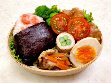 Düzgün düzenlenmiş pirinç, lezzetli protein ve çeşitli mezelerle dolu renkli bir dosirak beslenme çantası. Taşınabilir bir ziyafet, özgün Kore ev usulü yemeklerin özünü yansıtıyor..