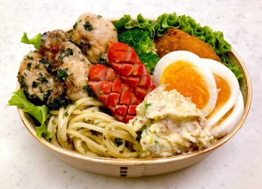 Düzgün düzenlenmiş pirinç, lezzetli protein ve çeşitli mezelerle dolu renkli bir dosirak beslenme çantası. Taşınabilir bir ziyafet, özgün Kore ev usulü yemeklerin özünü yansıtıyor..