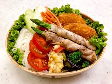 Düzgün düzenlenmiş pirinç, lezzetli protein ve çeşitli mezelerle dolu renkli bir dosirak beslenme çantası. Taşınabilir bir ziyafet, özgün Kore ev usulü yemeklerin özünü yansıtıyor..