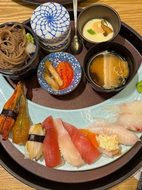 Çeşitli malzemeler ve canlı renklerle sanatsal olarak düzenlenmiş taze suşi çeşitleri. Bu geleneksel Japon yemeği bir deneyim için sirkeli pirinç, deniz ürünleri ve sebzeleri birleştirir..