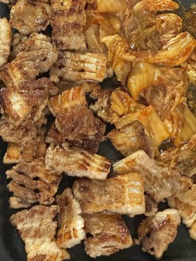 Izgara samgyeopsal, kalın domuz eti dilimleri çıtır çıtır ve taze et. Klasik bir Kore barbekü deneyimi için marul, sarımsak ve sosla servis ediliyor..