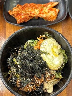 Cızırdayan sıcak dolsot bibibimbap, çıtır pilav, renkli sebzeler, marine edilmiş et, kızarmış yumurta ve gochujang ile servis edilir. Tat ve dokularla dolu bir Kore yemeği..