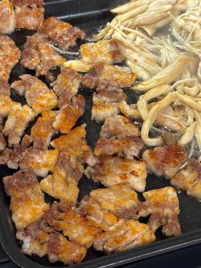 Izgara samgyeopsal, kalın domuz eti dilimleri çıtır çıtır ve taze et. Klasik bir Kore barbekü deneyimi için marul, sarımsak ve sosla servis ediliyor..