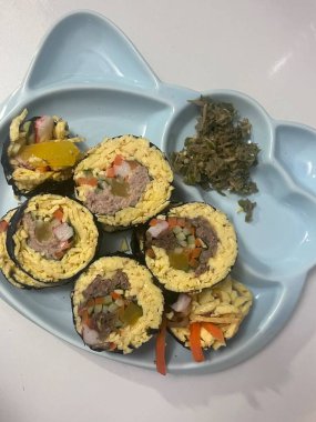 Taze sebzelerle, baharatlı pirinçlerle ve gevrek yosunlara sarılmış lezzetli proteinlerle dolu nefis kimbap dürümleri. Her ısırıkta lezzet ve dokuların mükemmel bir kombinasyonu.