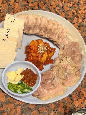 Yumuşak bir parça Bossam, Kore haşlanmış domuz göbeği, taze marul, sarımsak ve ssamjang ile servis edilir. Bu lezzetli ve lezzetli yemek geleneksel bir Kore yemeğini paketlemek ve paylaşmak için mükemmeldir..