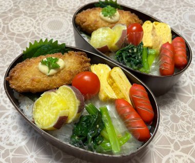 Geleneksel bir Kore dozirak 'ı. Pirinç, çeşitli banchan ve tuzlu proteinlerle güzelce düzenlenmiş. Dengeli ve görsel olarak davetkâr, canlı lezzetlerle dolu taşınabilir bir yemek..